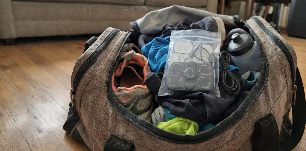 Portable muscle stimulator packed in a runner's gym bag